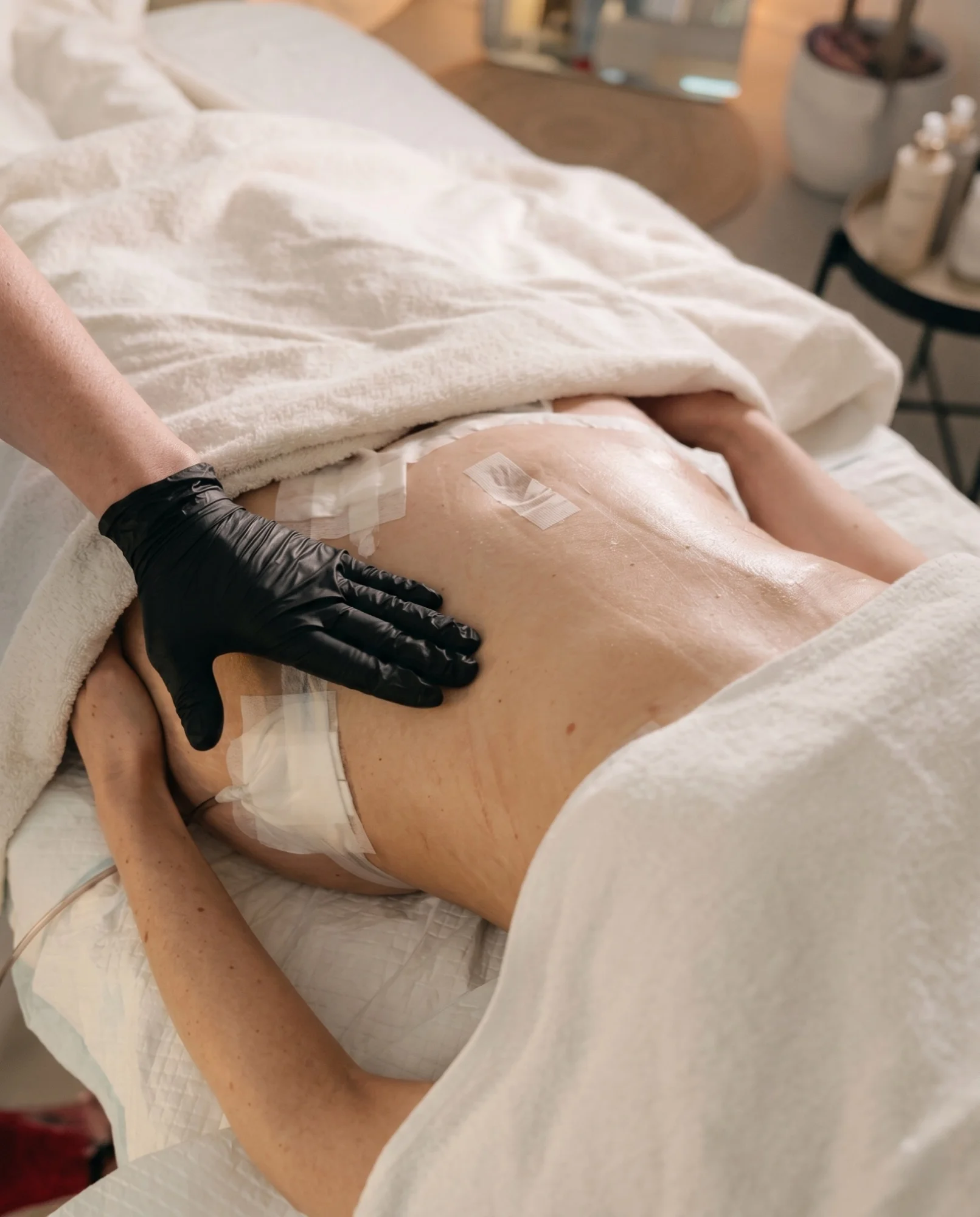 Détail des mains d'une kinésithérapeute appliquant une pression douce sur le dos d'une patiente